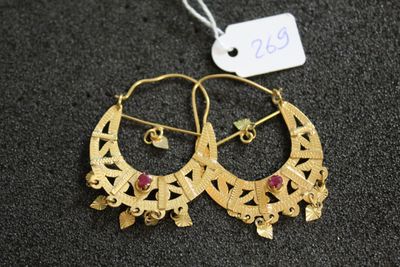 une paire de boucles d'oreilles créoles en or ornées de pierres rouges