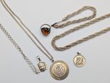 trois colliers en argent et deux breloques en argent sur un fond blanc