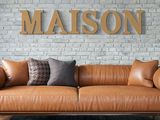 a brown leather couch sitting in front of a brick wall