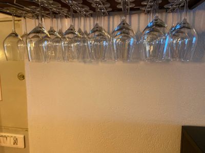 many wine glasses hanging from the wall above a wine glass rack