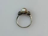 an image of a pearl and diamond ring on a white surface