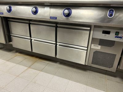 une grande cuisine en inox équipée de quatre fours intégrés au plan de travail