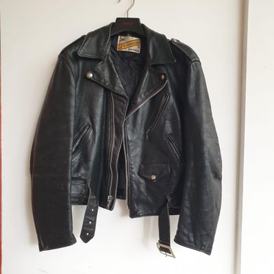 une veste en cuir noir accrochée à un mur blanc dans une pièce