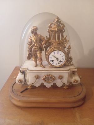 une horloge placée sous un dôme de verre sur une table