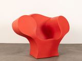 an orange chair sitting on top of a cement floor next to a white wall