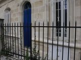 a blue door on a stone building behind a black fence