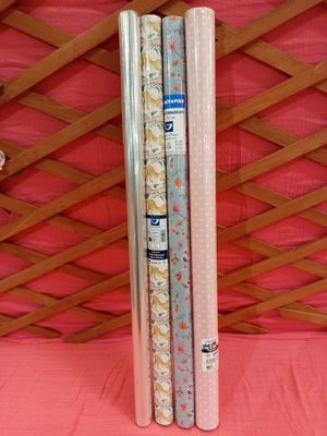 deux rouleaux de papier d'emballage posés sur une nappe rose