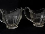 two clear glass pitchers sitting on top of a black surface