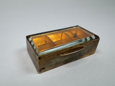 une petite boîte en verre avec un couvercle, posée sur une surface blanche