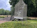 a bird cage sitting on top of a bench in the grass
