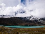 Des nuages recouvrent les montagnes et un lac au premier plan.
