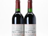 two bottles of red wine sitting next to each other on a white surface
