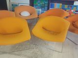 quatre chaises orange dans une pièce avec une bibliothèque