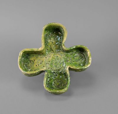 an image of a green cross shaped bowl with a face on it