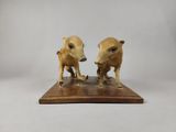 deux figurines représentant deux sangliers, posées sur un socle en bois