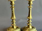 pair of antique brass candlesticks on a grey background