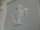 a white vase with flowers on it on the wall
