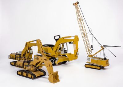 trois engins de chantier miniatures et une grue sur fond blanc