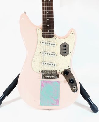 an electric guitar sitting on top of a stand on a white surface
