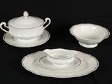 three pieces of white and silver dinnerware on a black table