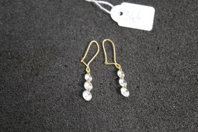 une paire de boucles d'oreilles posée sur une surface noire, avec une étiquette de prix
