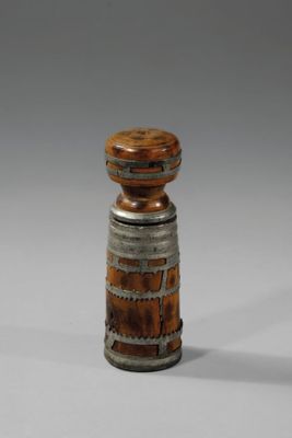 une image représentant un vase en bois et en métal posé sur une surface blanche