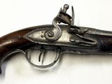 un vieux pistolet avec une poignée en bois sur une surface blanche