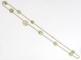 a close up of a gold bracelet with green stones on it
