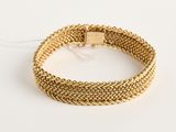 gros plan d'un bracelet en or sur une surface blanche