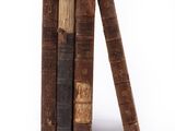 several old books stacked on top of each other on a white surface