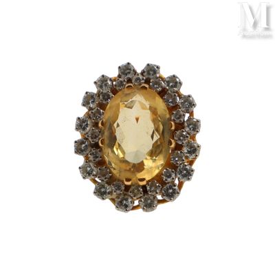 une photo d'une bague ornée d'une grosse pierre jaune entourée de petits diamants blancs