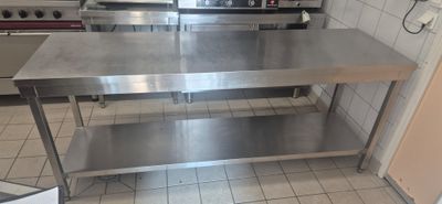 a stainless steel table in a kitchen with a stove in the background