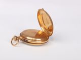 a small gold pocket watch on a white surface
