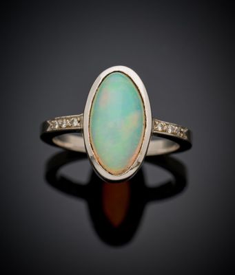 une bague en oplite blanche sertie d'un diamant, posée sur un fond noir