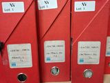 three red binders are on a shelf with labels on them