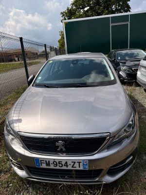 La voiture argentée est garée devant un parking clôturé.