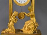 a gold clock with a woman holding a sunflower on it
