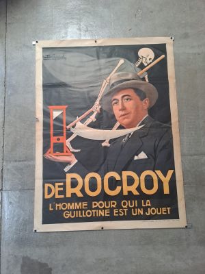 une affiche accrochée au mur d'un immeuble, sur laquelle figure la photo d'un homme coiffé d'un chapeau