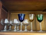 several wine glasses are lined up on a shelf in a cabinet