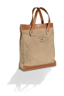 Le sac fourre-tout en toile avec des anses en cuir est de couleur beige et marron