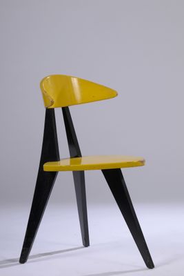 chaise jaune aux pieds noirs, avec une assise en bois posée sur une surface blanche