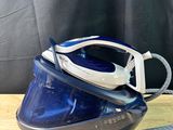 a blue and white steam iron on a wooden table