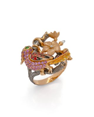 un gros plan d'une bague ornée d'un oiseau et de fleurs