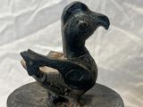 statue of a bird on a wooden base with a white background