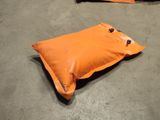 an orange pillow sitting on the floor next to a pair of scissors