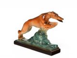 figurine représentant un chien sautant par-dessus un rocher sur fond blanc