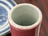 a red cup sitting on a table next to a blue and white plate