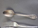 two silver spoons and a fork on a table