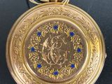 a gold pocket watch with blue stones on it