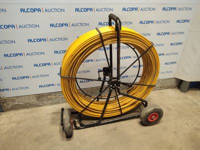 a yellow hose on a cart in front of a wall
